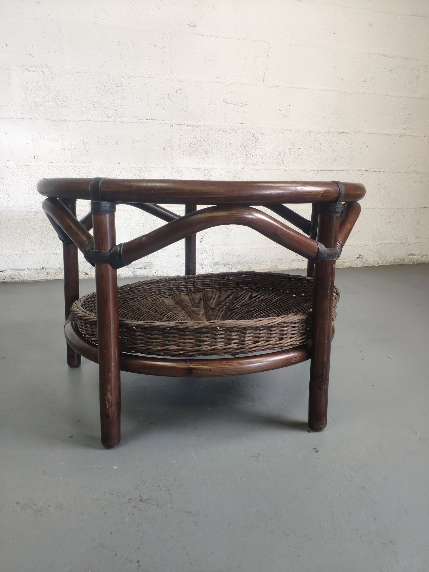 Table basse vintage en rotin avec le plateau en verre fumé et étagère panier en rotin.