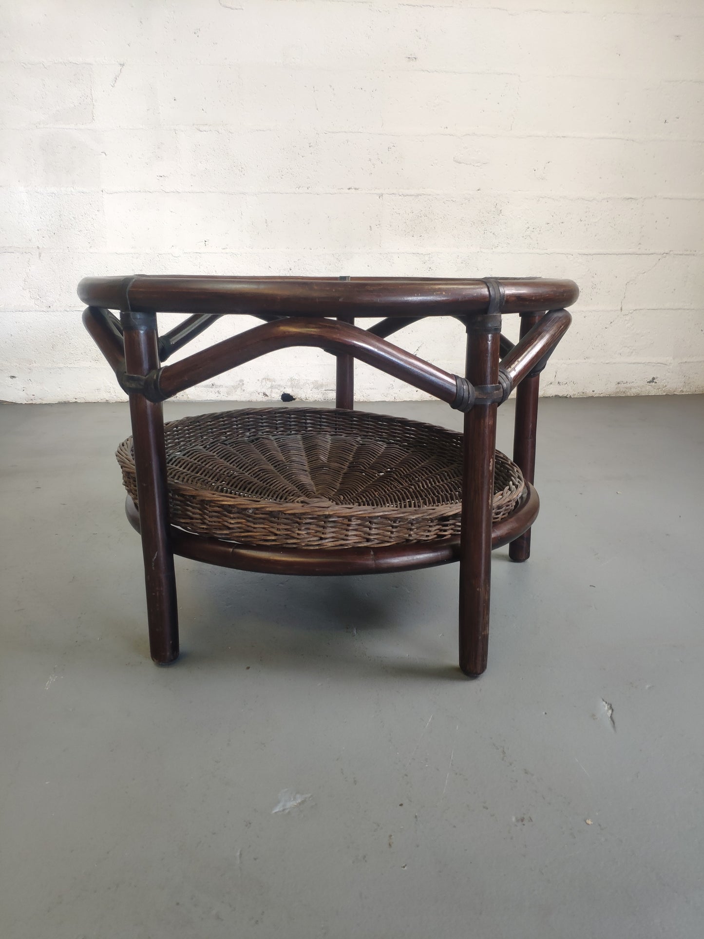 Table basse vintage en rotin avec le plateau en verre fumé et étagère panier en rotin.