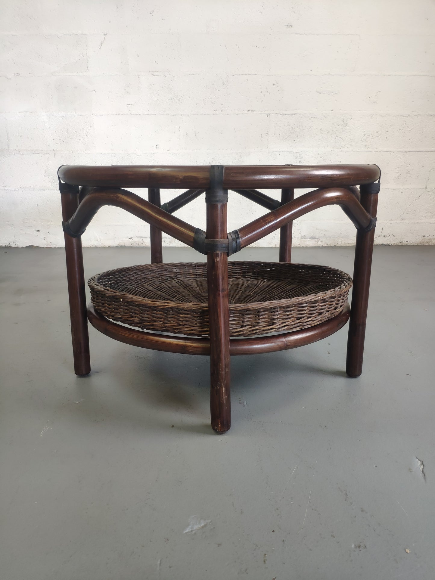 Table basse vintage en rotin avec le plateau en verre fumé et étagère panier en rotin.