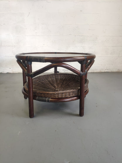 Table basse vintage en rotin avec le plateau en verre fumé et étagère panier en rotin.