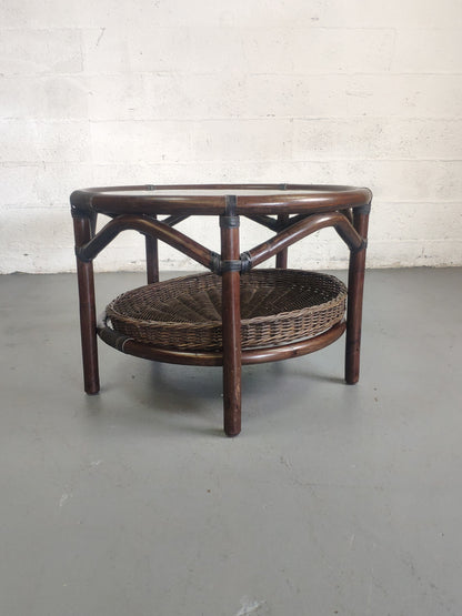 Table basse vintage en rotin avec le plateau en verre fumé et étagère panier en rotin.