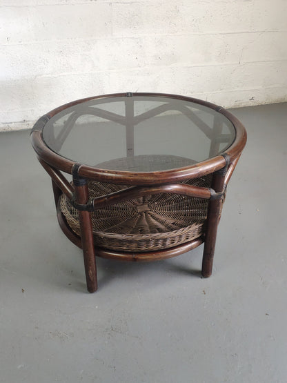 Table basse vintage en rotin avec le plateau en verre fumé et étagère panier en rotin.