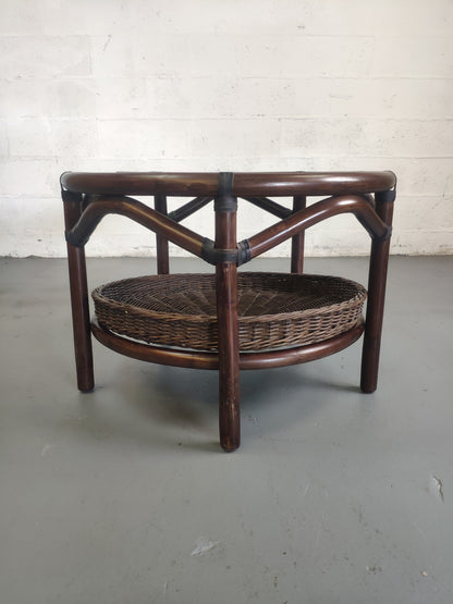 Table basse vintage en rotin avec le plateau en verre fumé et étagère panier en rotin.